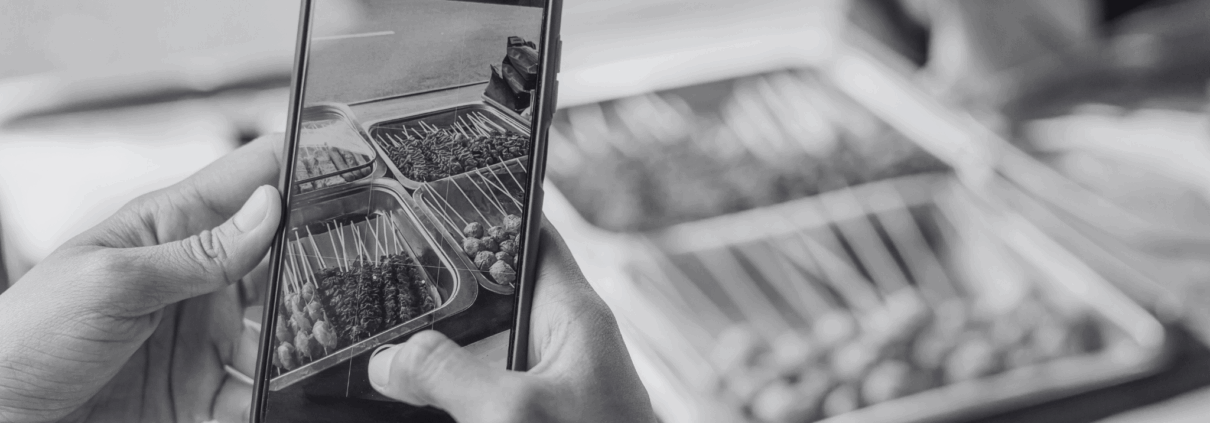 Person holding a phone, recording a reel of food.
